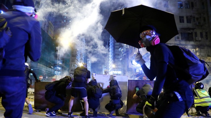 Protesters take cover behind boards during a protest in the Mong Kok area in Hong Kong